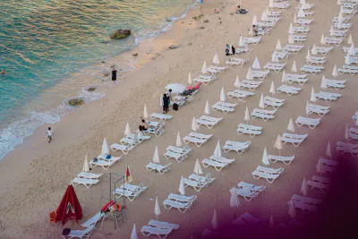 Șezlonguri și umbrele pe plajă cu mare turcoaz lângă un hotel de lux, Turcia